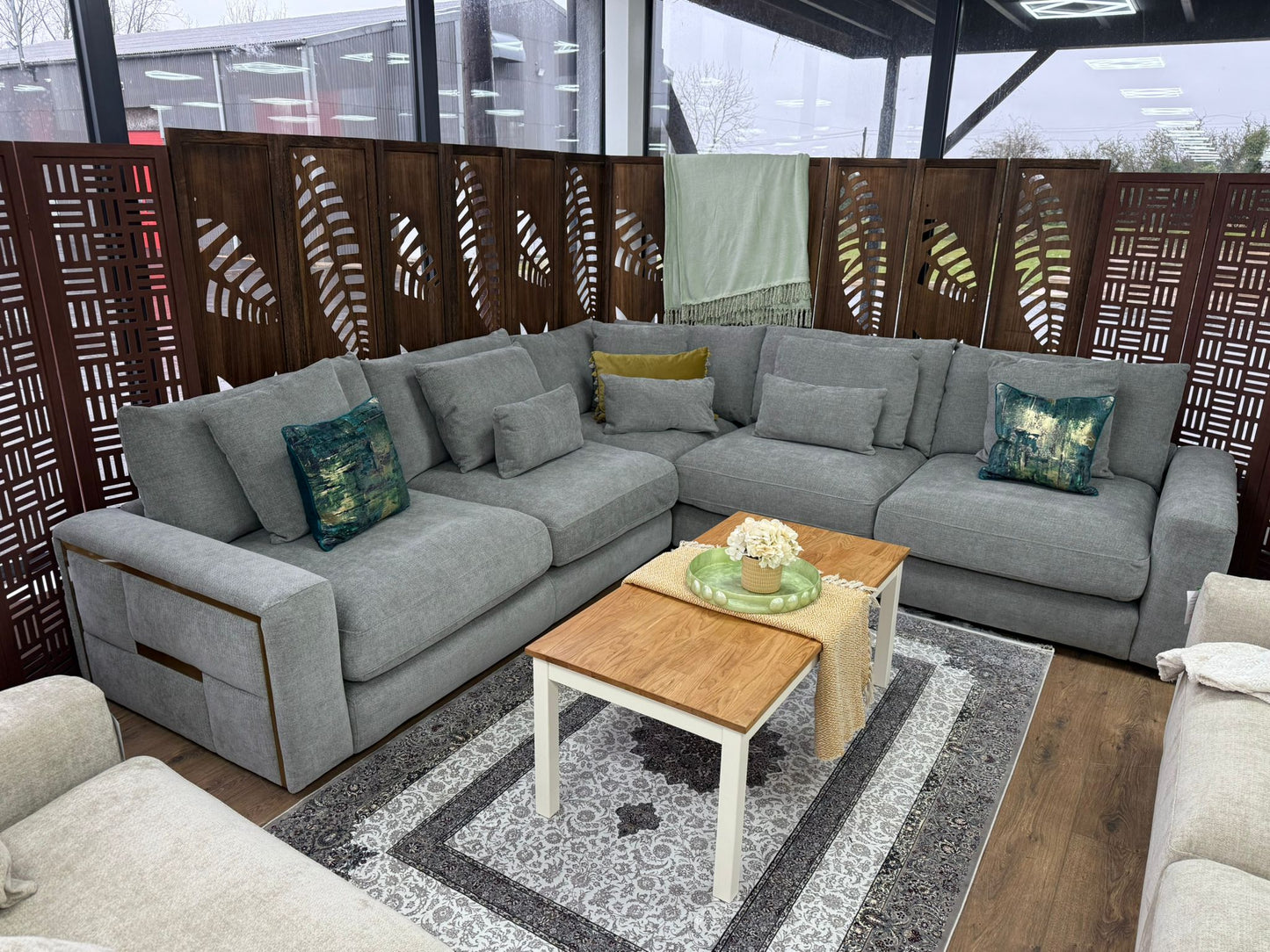 Gray sectional sofa with decorative pillows in a room with a wooden floor and decorative screen.