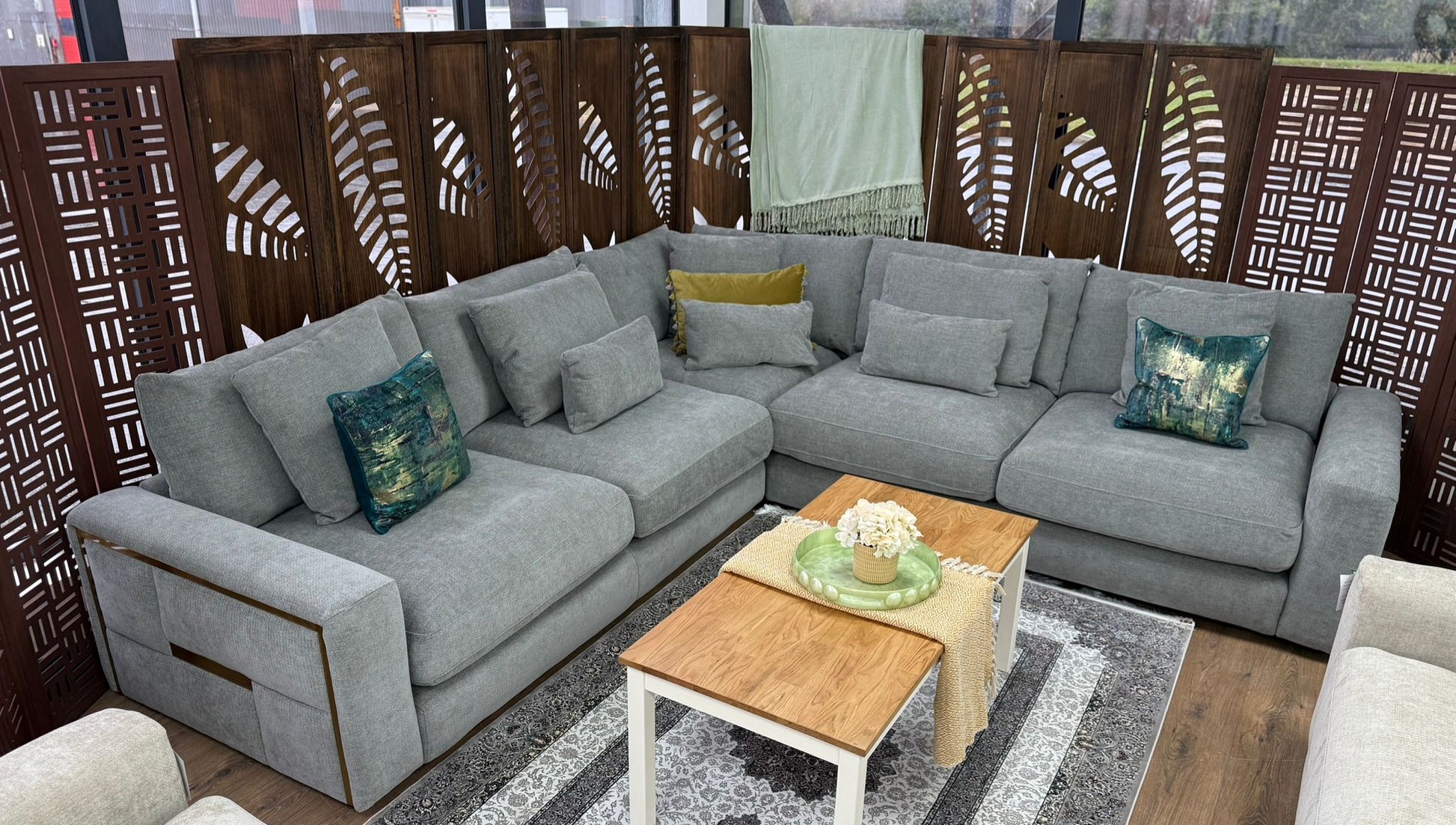 Gray sectional sofa with decorative pillows in a room with wooden screens and a rug.