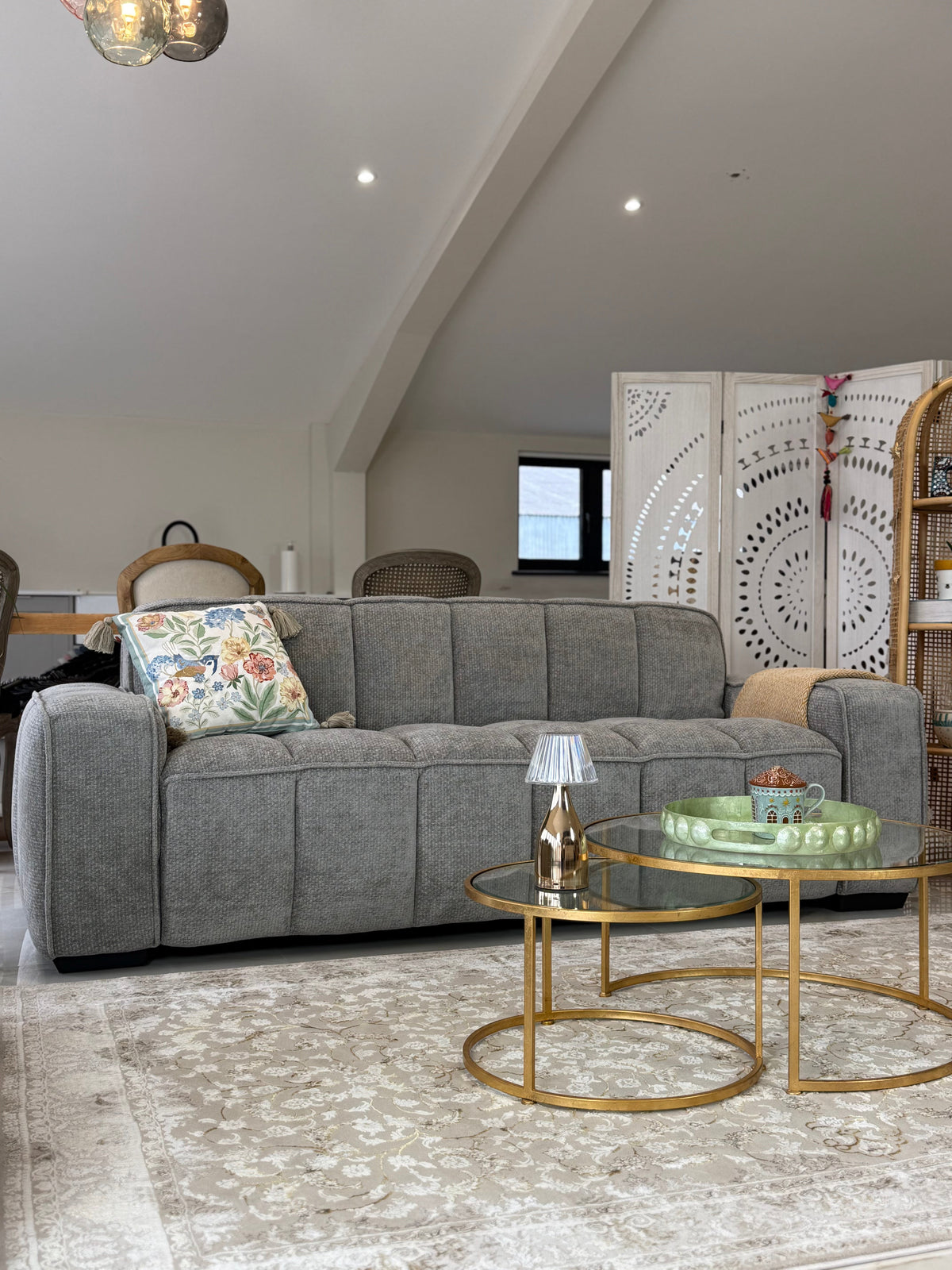 Living room with a gray sofa, gold coffee table, and decorative elements.