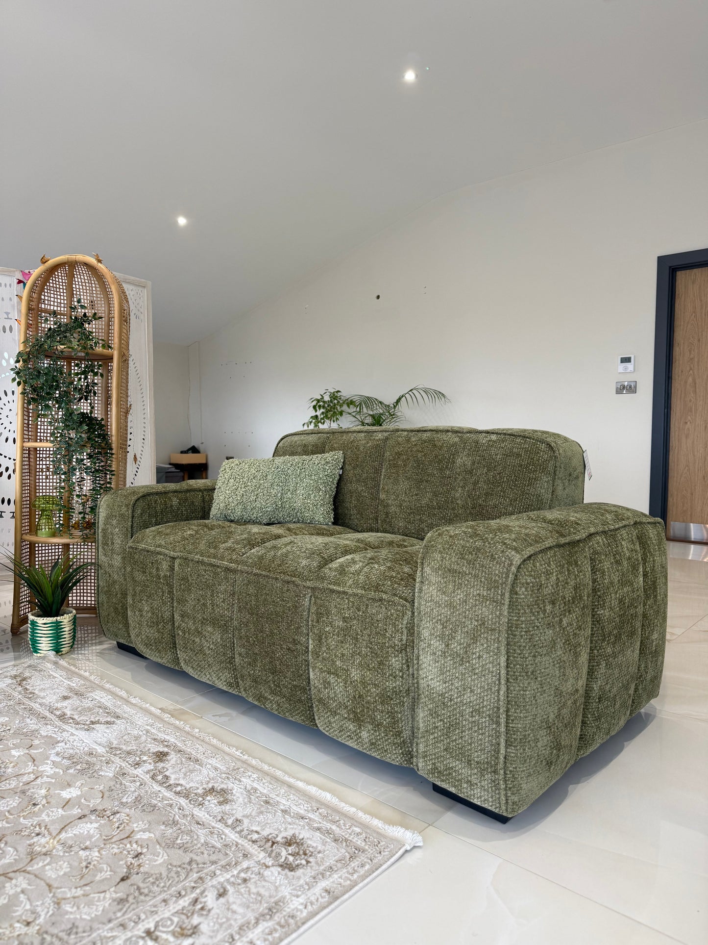Green sofa in a living room with a white wall and decorative elements.