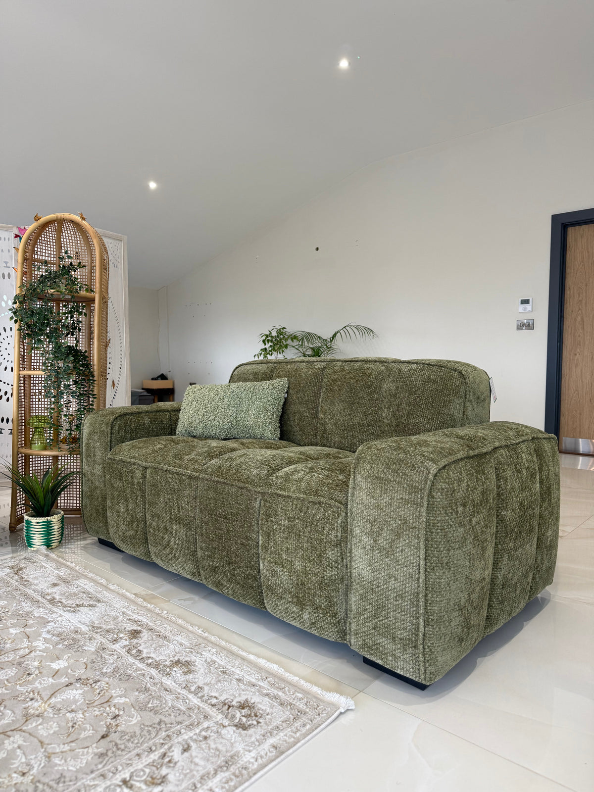 Green sofa in a living room with a white wall and decorative elements.