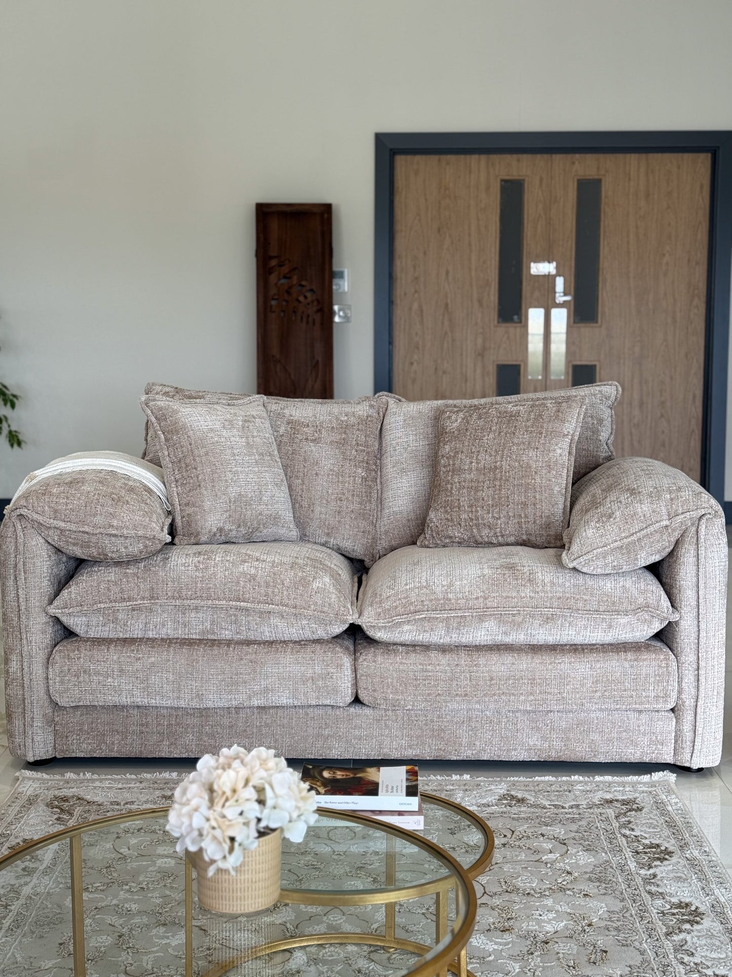 Beige sofa in a living room with a glass coffee table and decorative elements.