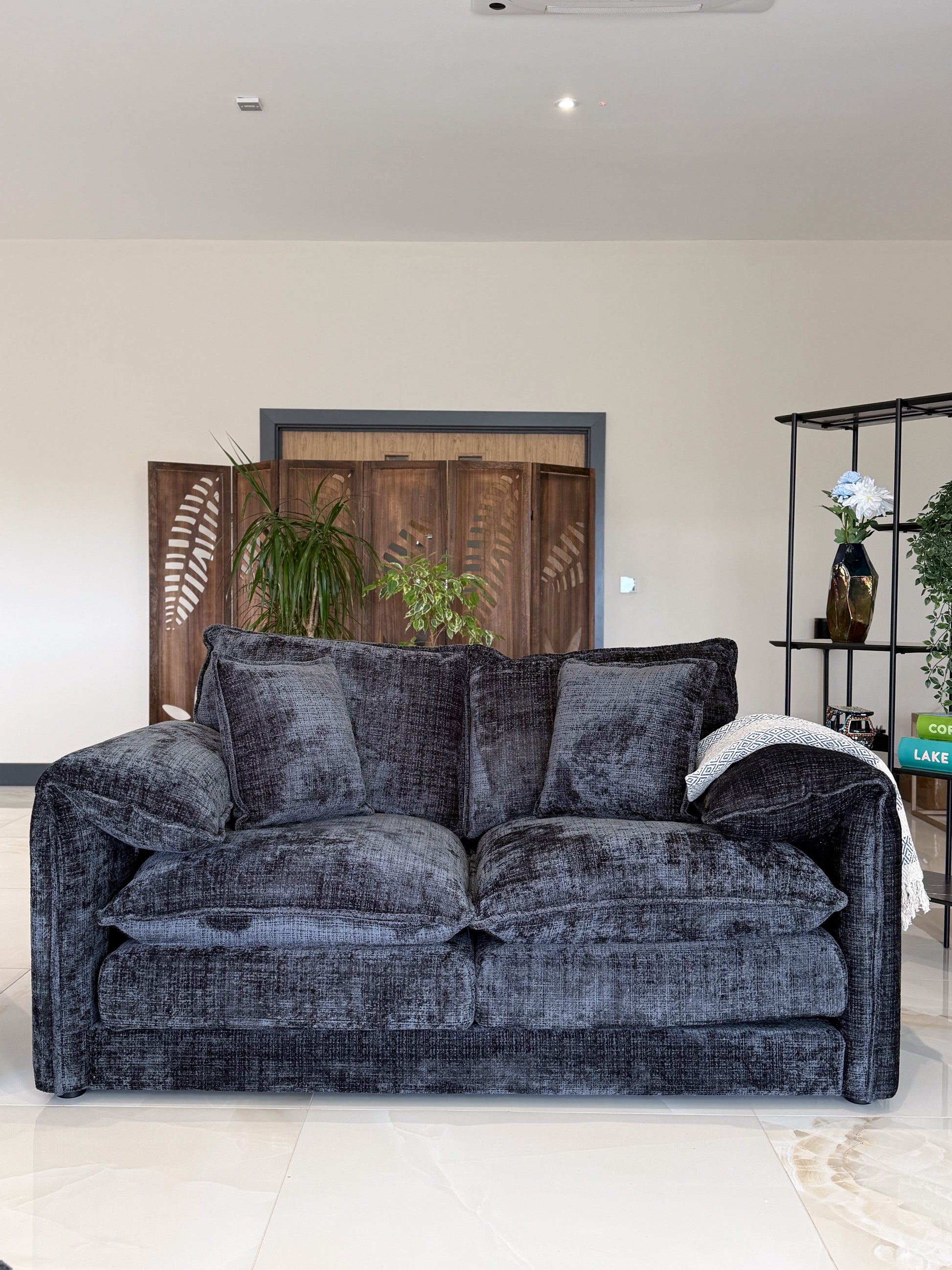 Black velvet sofa in a living room setting with decor elements.