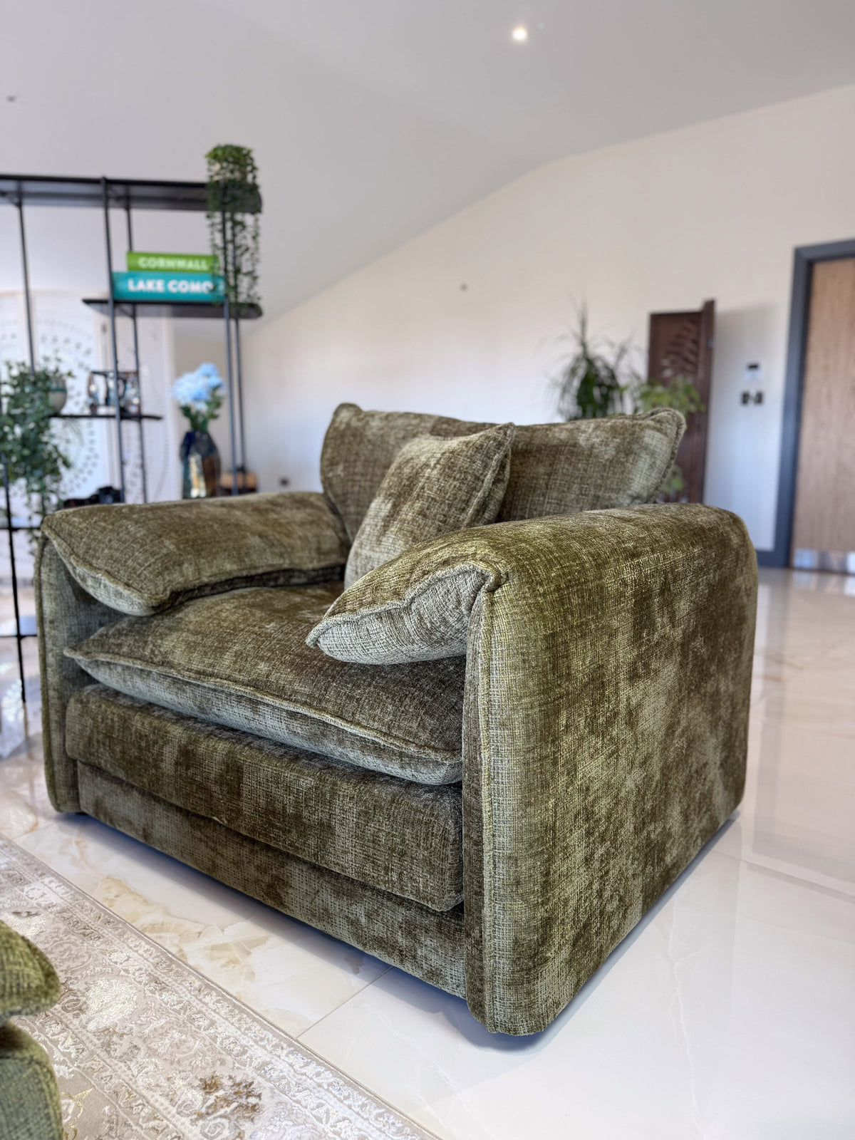 Green textured sofa in a room with white walls and a door.