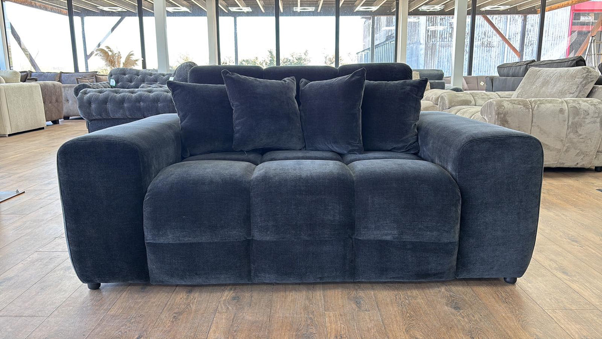 black sofa with three dark pillows in a showroom setting