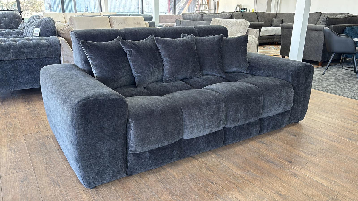 black sectional sofa in a showroom setting with other furniture in the background.
