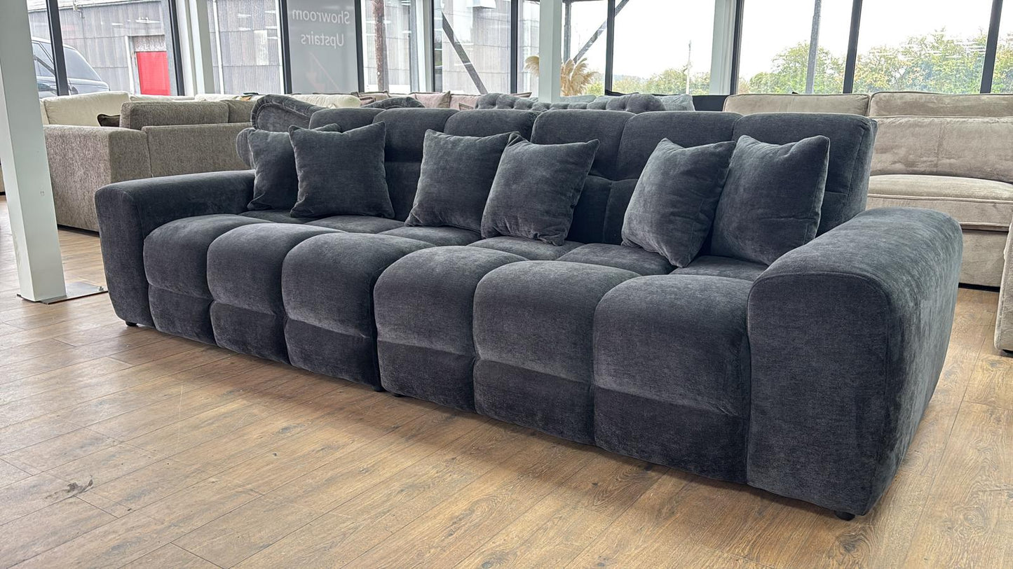Large Black sectional sofa in a room with large windows.