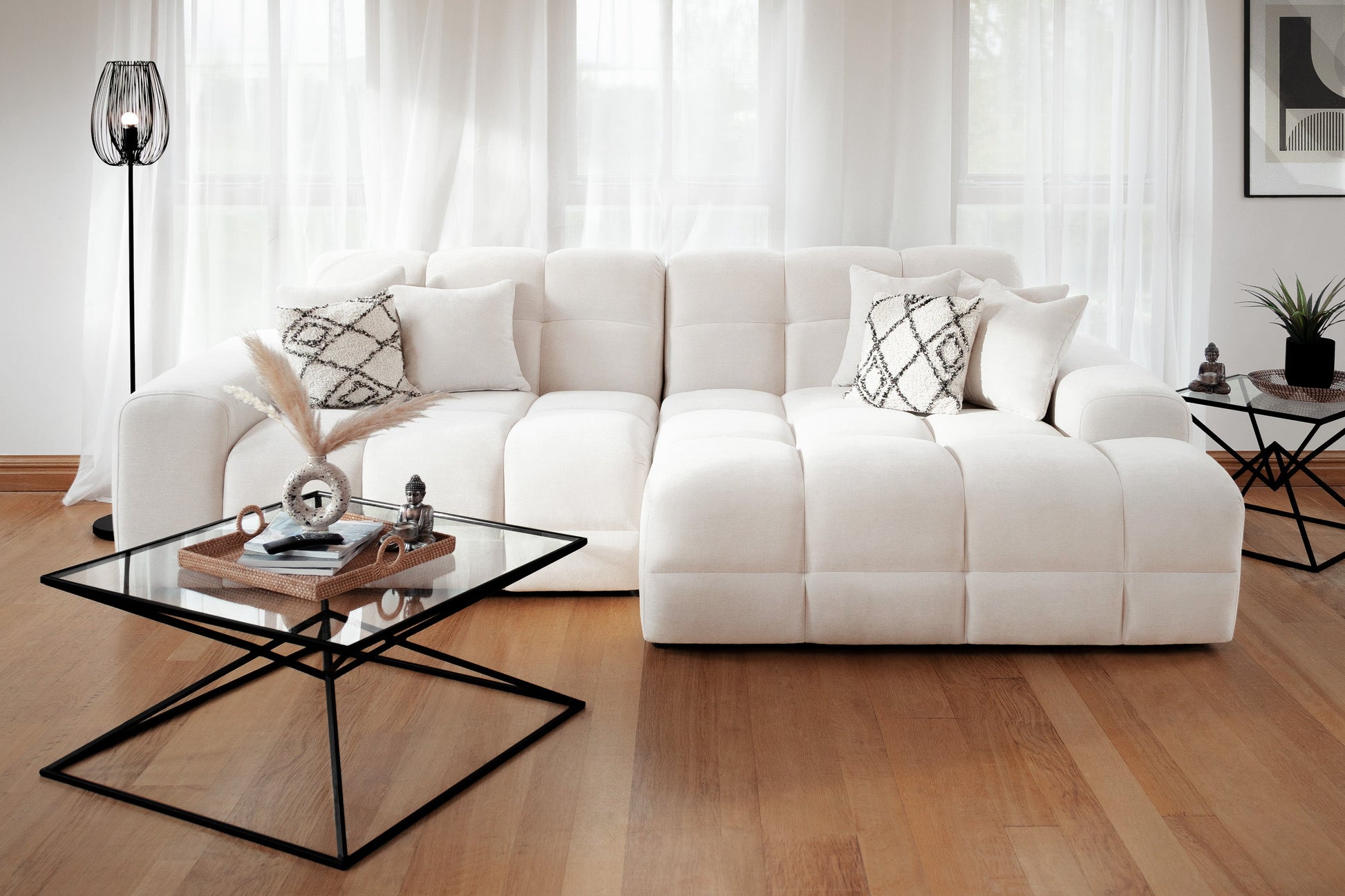 Modern living room with a white sectional sofa and glass coffee table.