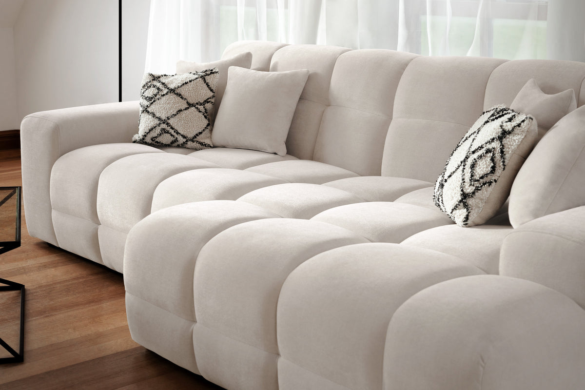 Beige sectional sofa with patterned cushions in a living room setting.