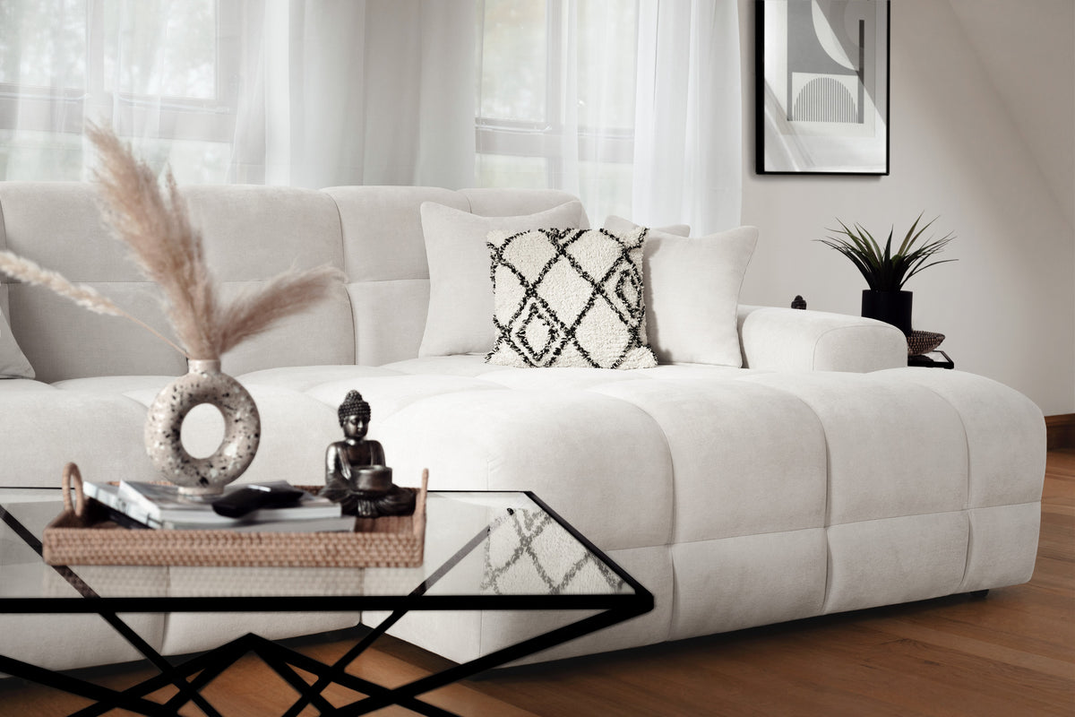 Modern living room with a white sofa, decorative pillows, and a glass coffee table.