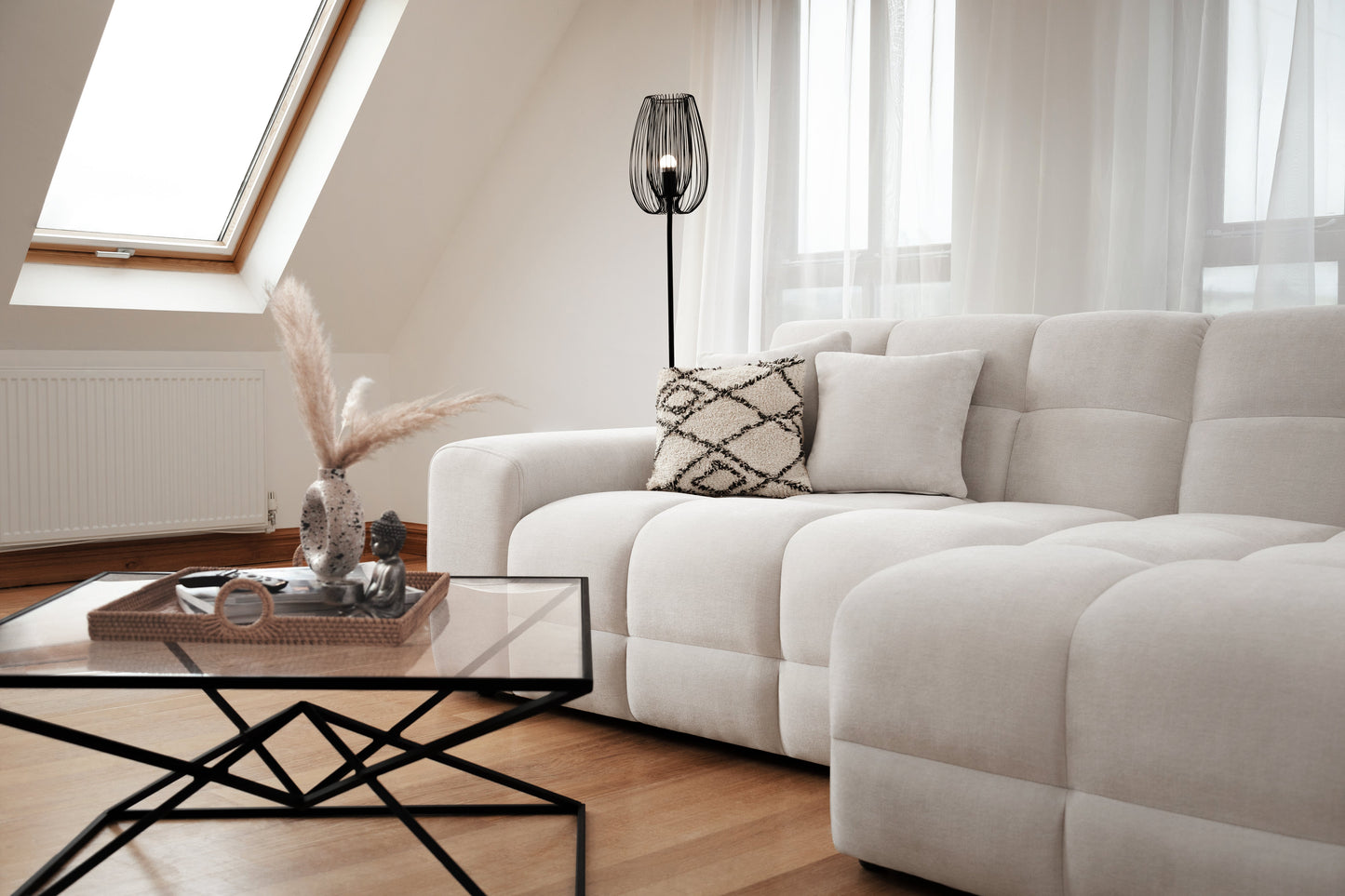 Modern living room with a white sofa, glass coffee table, and decorative elements.