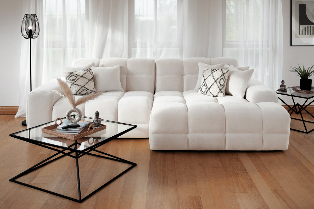 White sectional sofa in a living room with a glass coffee table and decorative items.
