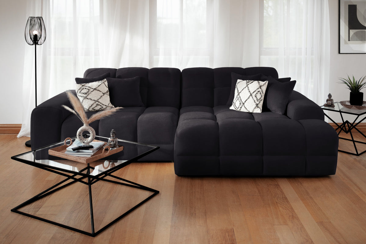 Black sectional sofa in a living room with a coffee table and decorative items.