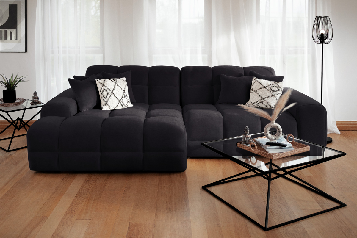 Modern living room with a black sectional sofa and glass coffee table.