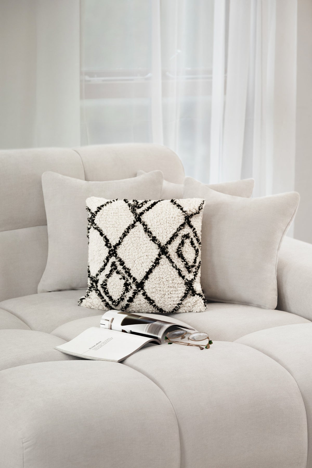 Gray sofa with decorative pillows and a handbag on a light background