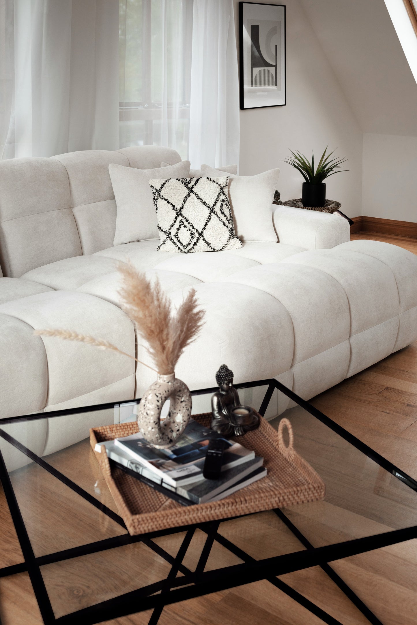 Modern living room with a white sofa, glass coffee table, and decorative items.
