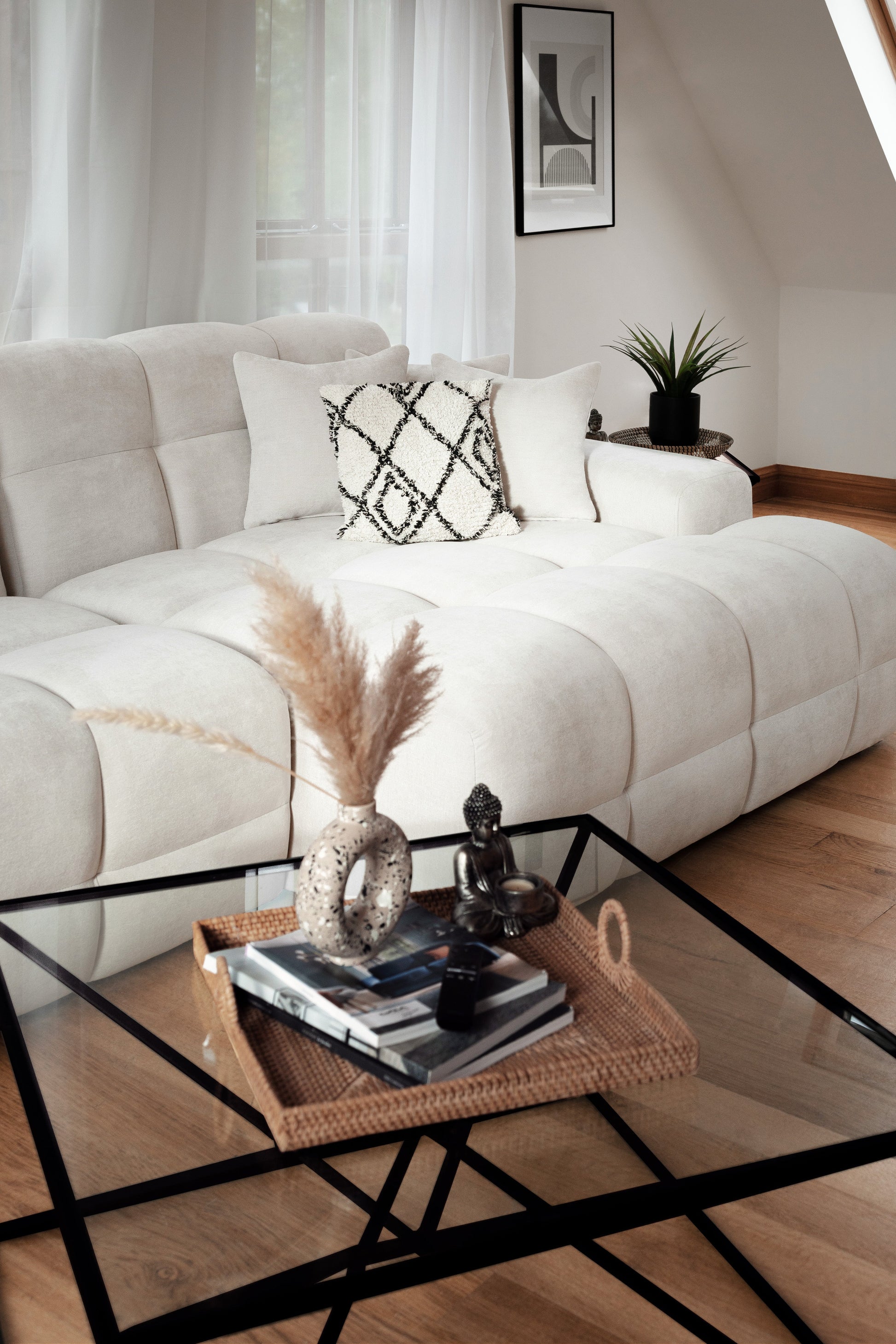 Modern living room with a white sofa, glass coffee table, and decorative items.