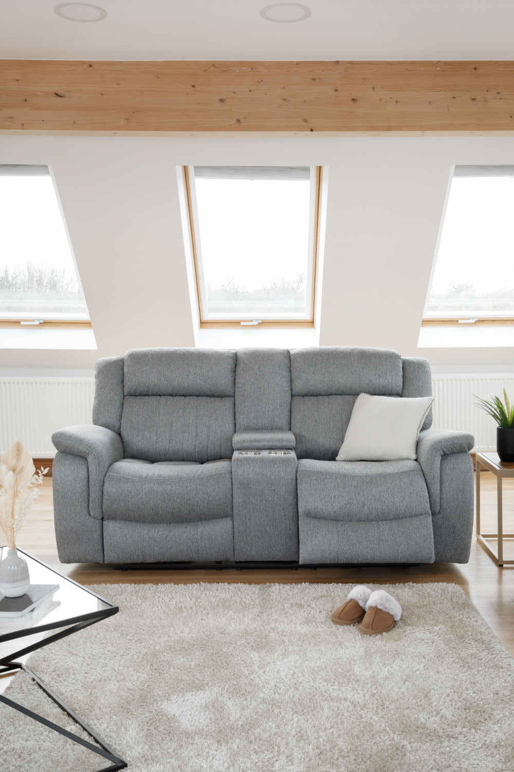 Gray sofa in a modern living room with large windows and wooden beams.