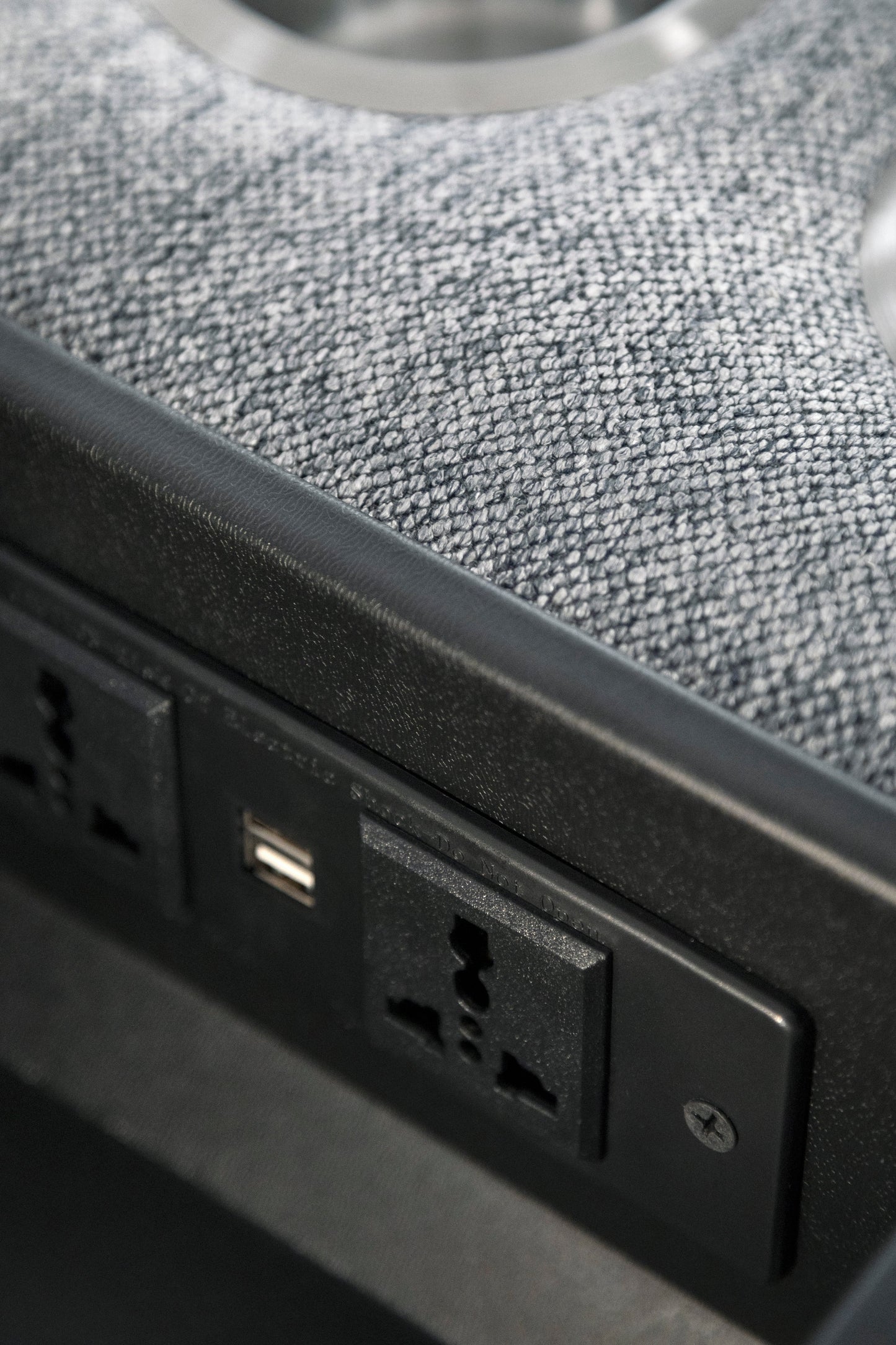Close-up of a power strip with multiple outlets and USB ports on a textured surface.