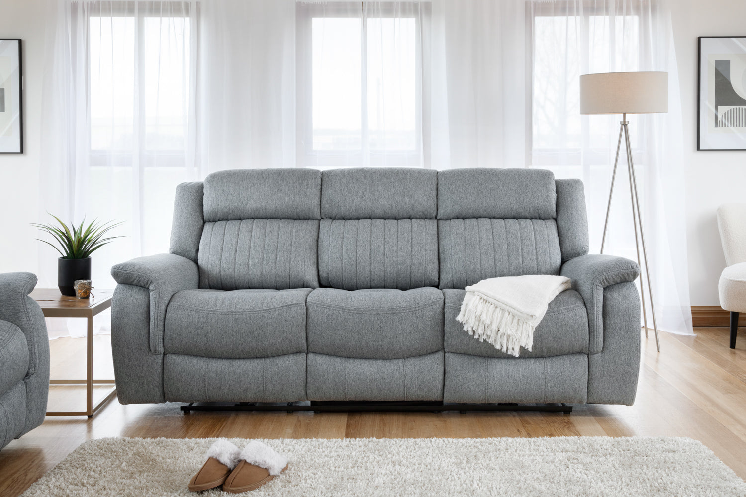 Gray sofa in a living room with a lamp and small table.