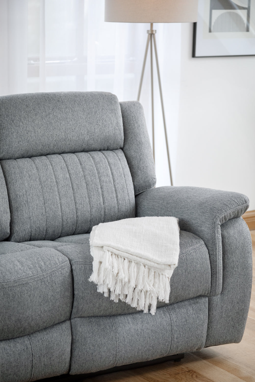Gray sofa with a white blanket draped over it in a living room setting.