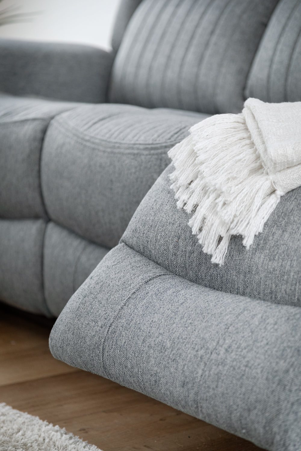 Gray sofa with a white blanket on a wooden floor