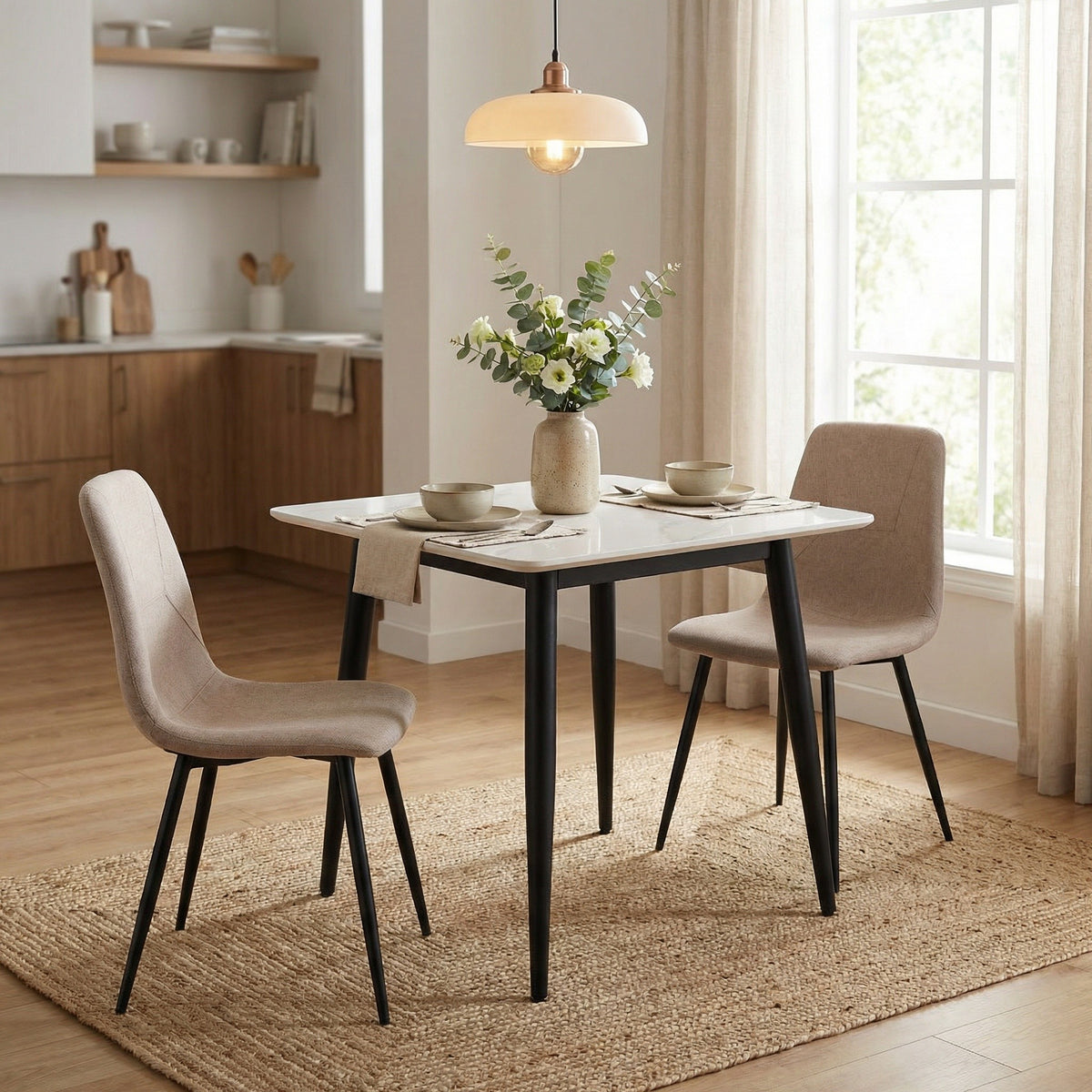 Dining room with a table and chairs, flowers, and kitchen in the background.