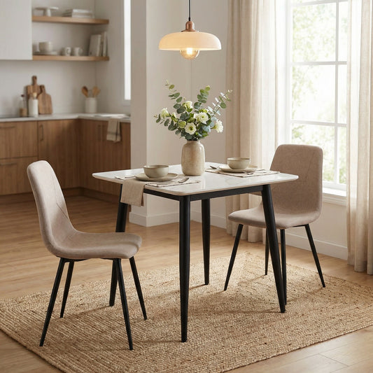 Dining room with a table and chairs, flowers, and kitchen in the background.