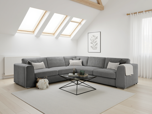 Gray sectional sofa in a modern living room with skylights and a rug.