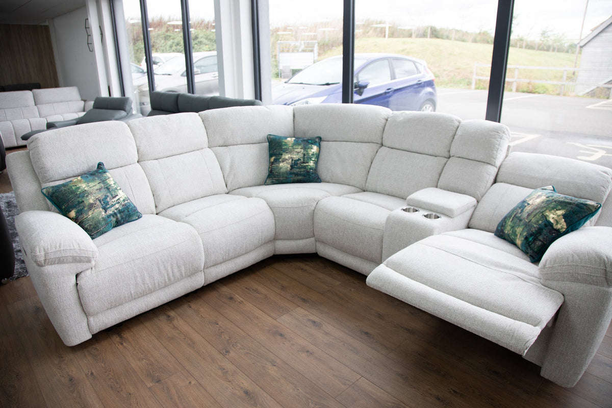 White sectional sofa with green cushions in a room with large windows.