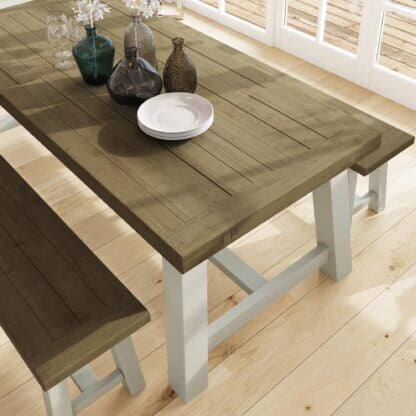 Wooden dining table with benches and decorative items in a bright room.