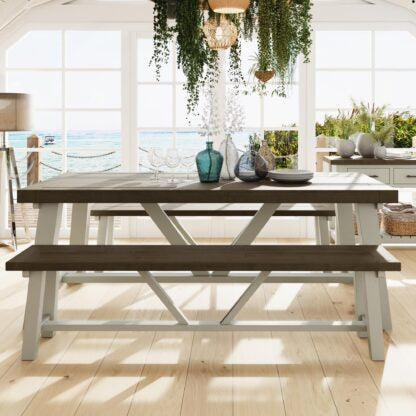 Outdoor dining table with benches in a bright room with large windows.