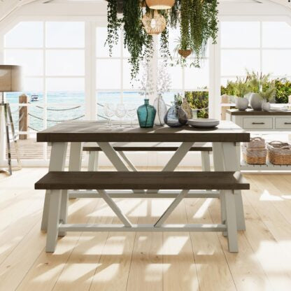 1.6m Wooden dining table with benches in a bright room with large windows.