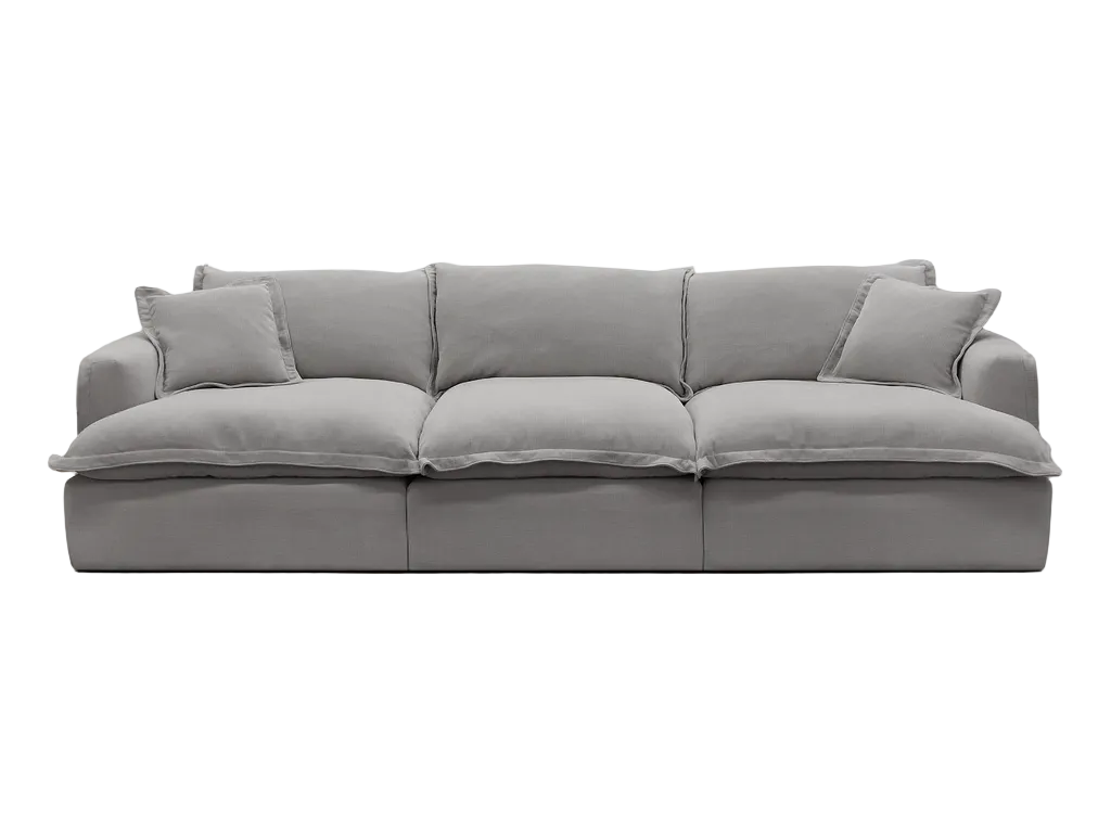 Gray sectional sofa in a living room with a round rug and a lamp.