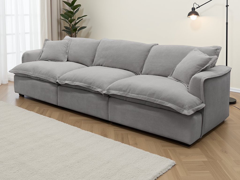Gray sofa in a living room setting with a lamp and plant in the background.