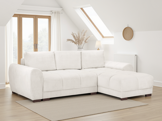 White sectional sofa in a bright living room with wooden floor and large windows.