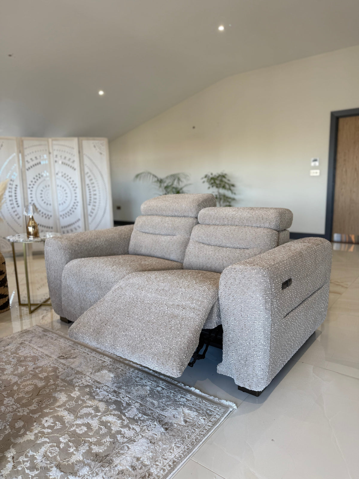 Beige recliner sofa in a modern living room with a decorative rug and wall art.