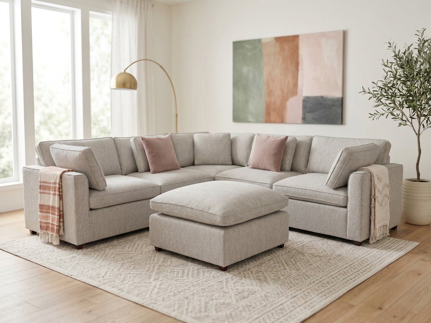 Light gray sectional sofa in a living room with a abstract painting on the wall.