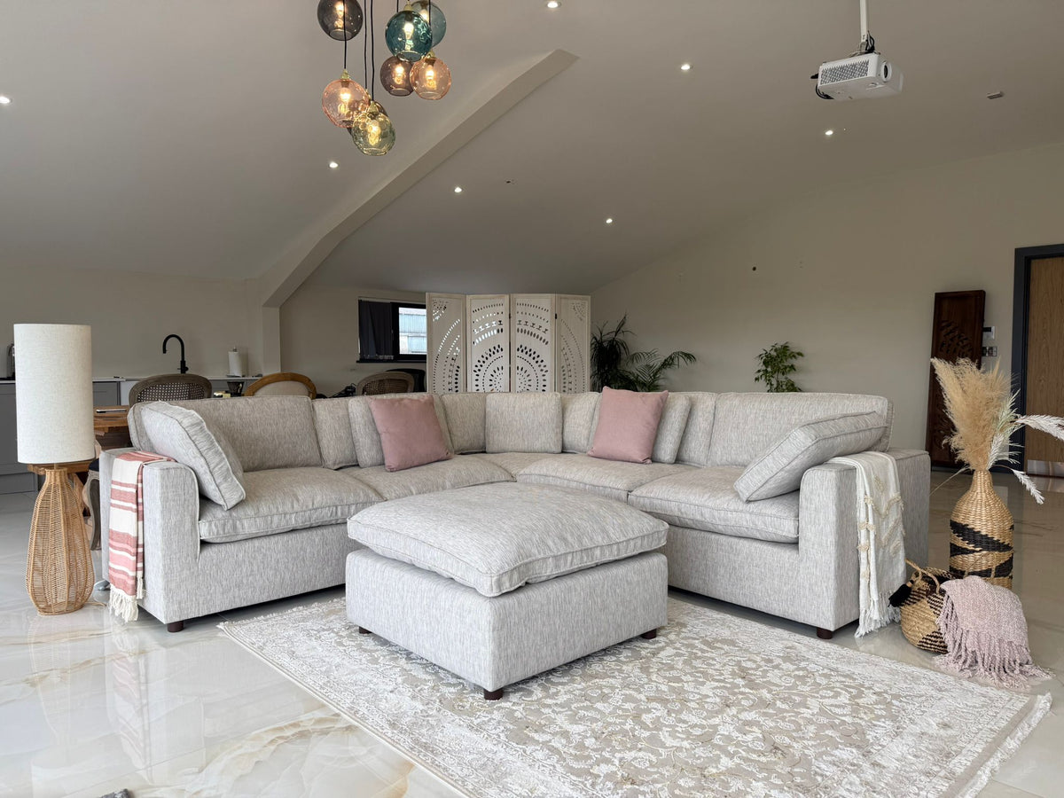 Modern living room with a gray sectional sofa, ottoman, and decorative pillows.