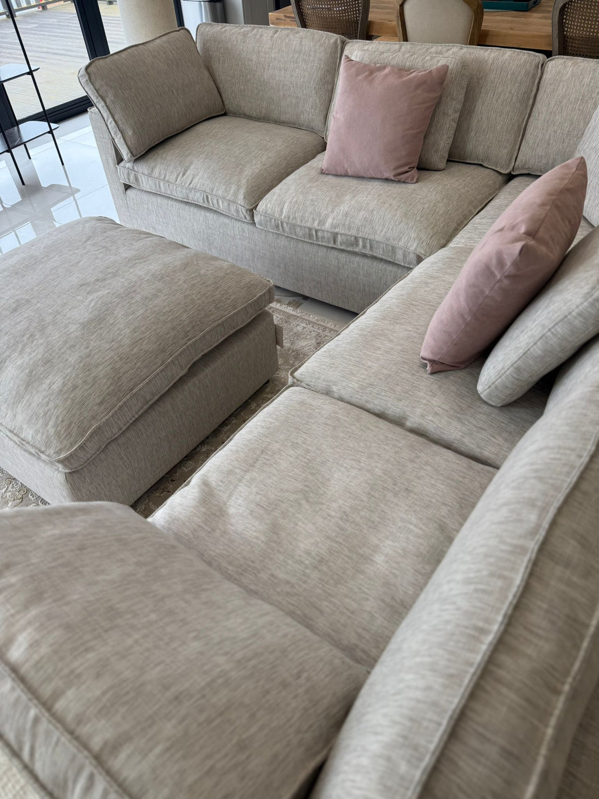 Grey sectional sofa with pink cushions in a living room setting