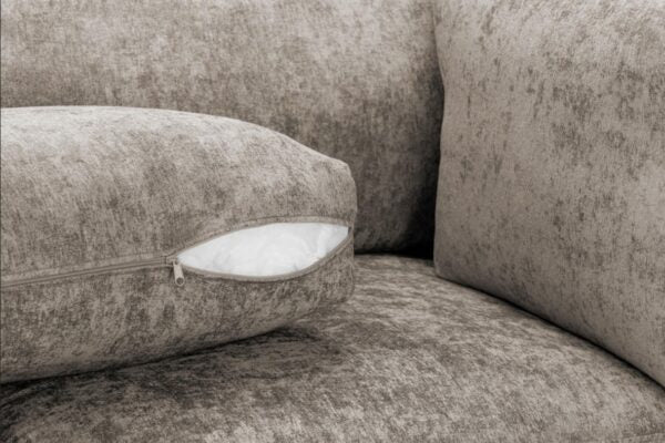 Close-up of a textured gray sofa with a cushion featuring a zipper.