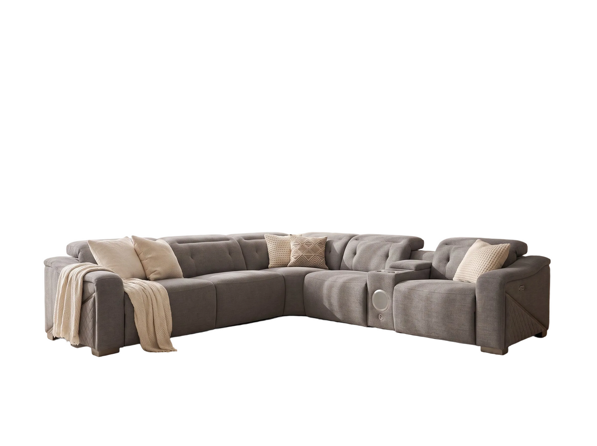 A modern L-shaped sectional grey sofa upholstered in textured taupe fabric, styled with beige throw pillows and a draped cream throw blanket, set against a plain white background.