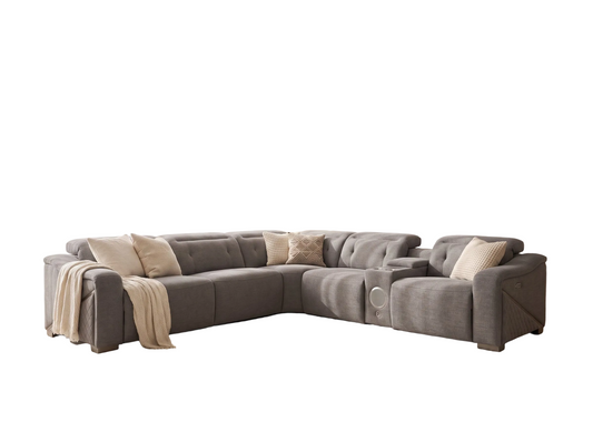 A modern L-shaped sectional grey sofa upholstered in textured taupe fabric, styled with beige throw pillows and a draped cream throw blanket, set against a plain white background.