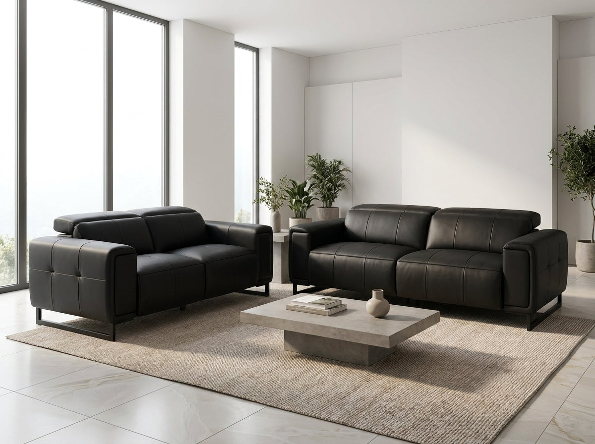 A modern living room setup featuring a black leather loveseat and a matching black leather three-seater sofa.