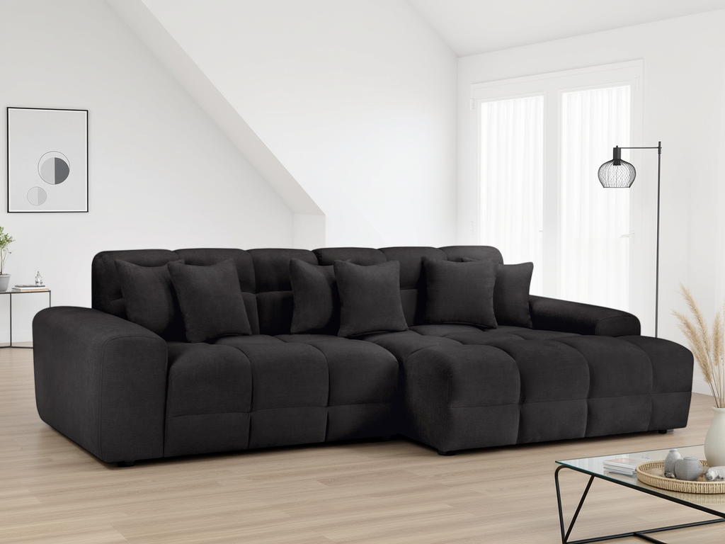 Black sectional sofa in a modern living room with large windows.