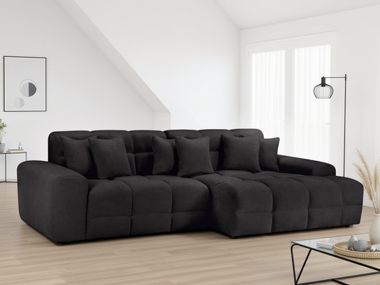 Black sectional sofa in a modern living room with large windows.