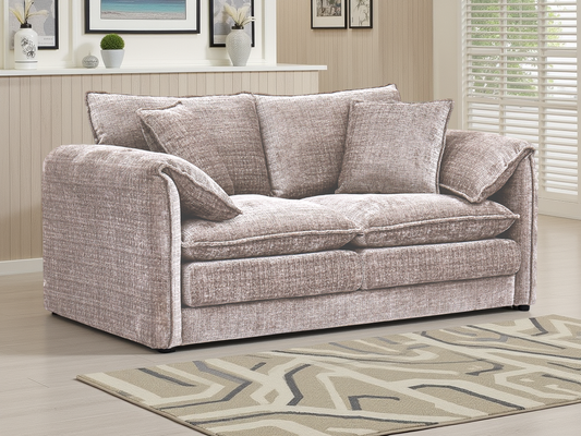 Beige sofa in a living room with a patterned rug and framed pictures on the wall.