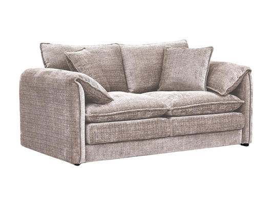 Beige sofa in a living room with a patterned rug and framed pictures on the wall.
